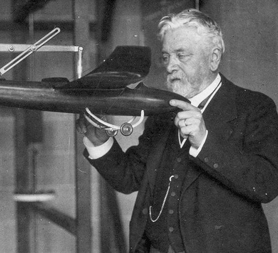 Gustave Eiffel dans son laboratoire tient une maquette de l'avion conçu par Victor Tatin