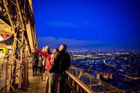 Una pareja tomándose una foto con copas de champán en el segundo piso de la Torre Eiffel