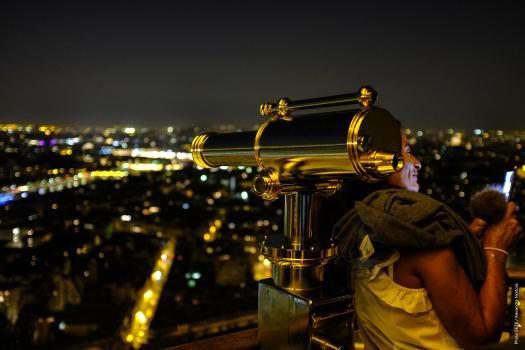 Femme avec son téléphone à la tour Eiffel de nuit